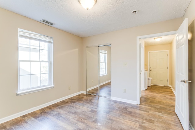 unfurnished bedroom featuring a closet, light hardwood / wood-style flooring, and multiple windows