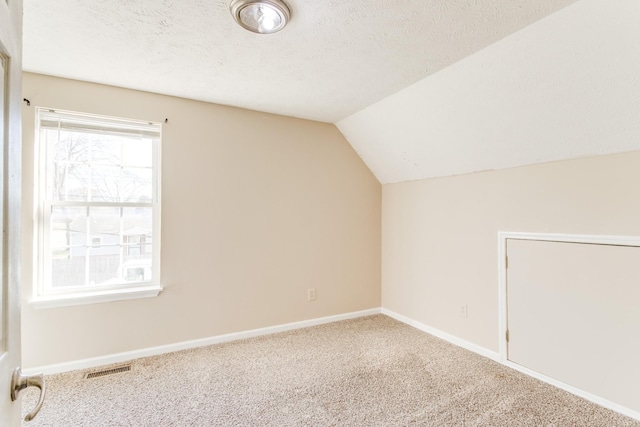 bonus room with carpet, a textured ceiling, and vaulted ceiling