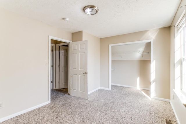 unfurnished bedroom featuring track lighting, light colored carpet, a textured ceiling, and a closet