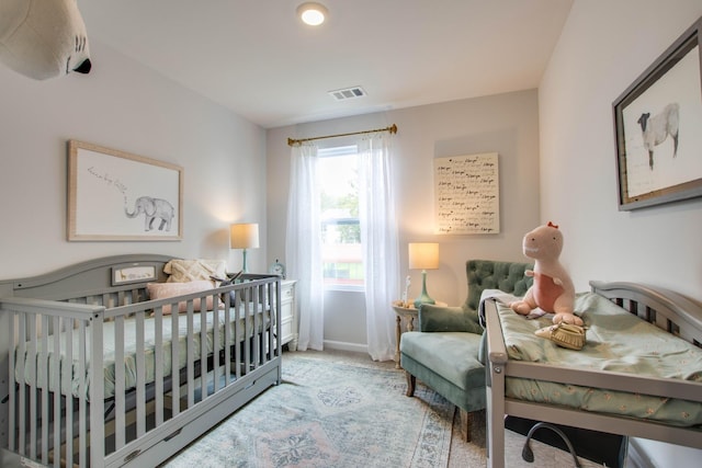 bedroom featuring light carpet and a nursery area