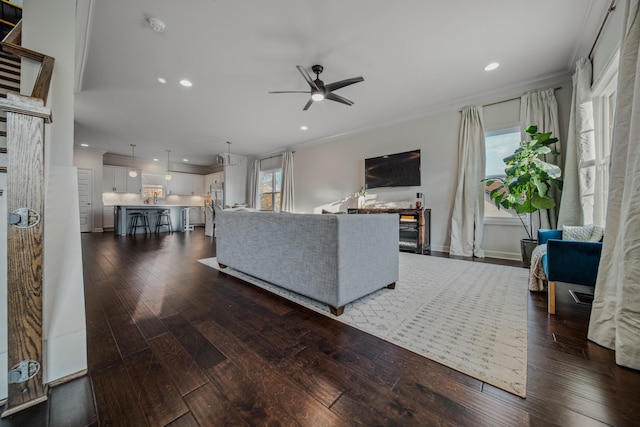 living room featuring dark hardwood / wood-style floors, ceiling fan, and ornamental molding