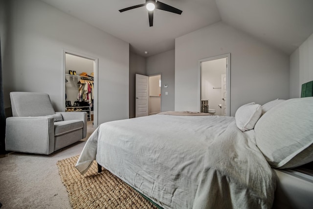 carpeted bedroom featuring lofted ceiling, a walk in closet, ensuite bath, ceiling fan, and a closet