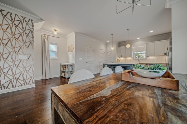 dining space featuring dark hardwood / wood-style flooring, crown molding, and sink