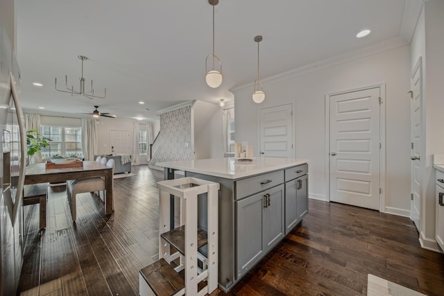 kitchen with decorative light fixtures, a kitchen island, dark hardwood / wood-style flooring, and ceiling fan with notable chandelier