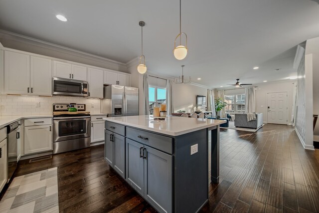 kitchen featuring appliances with stainless steel finishes, ceiling fan, dark hardwood / wood-style floors, a kitchen island, and hanging light fixtures