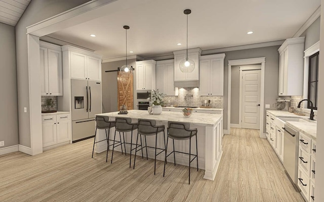 kitchen with sink, a barn door, light stone counters, white cabinetry, and stainless steel appliances