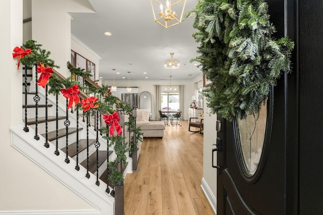 entryway with a chandelier, light hardwood / wood-style floors, and ornamental molding