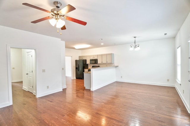 unfurnished living room with hardwood / wood-style floors and ceiling fan with notable chandelier