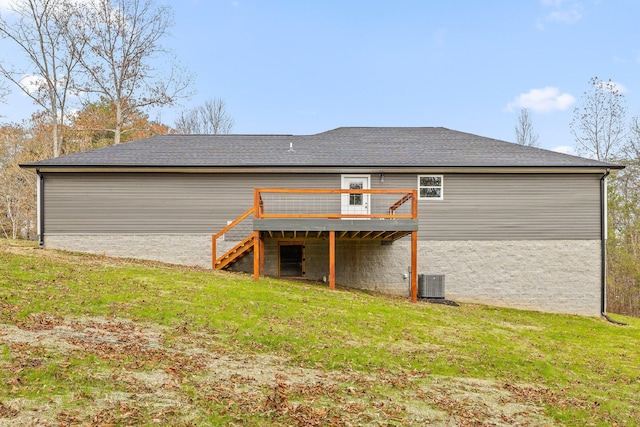 rear view of house with central AC unit, a wooden deck, and a lawn