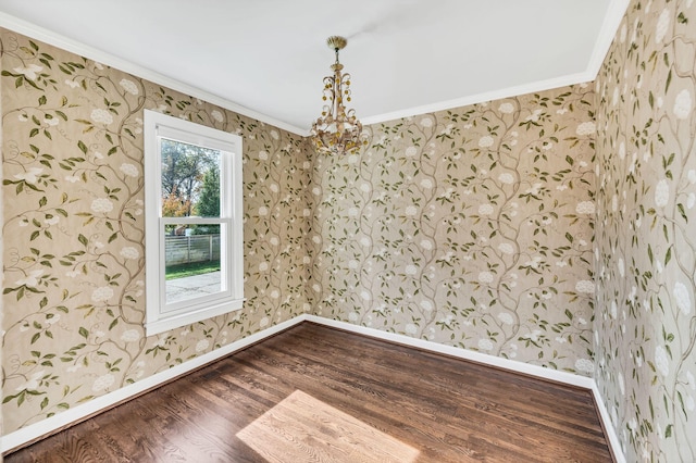 unfurnished room featuring an inviting chandelier, hardwood / wood-style flooring, and crown molding