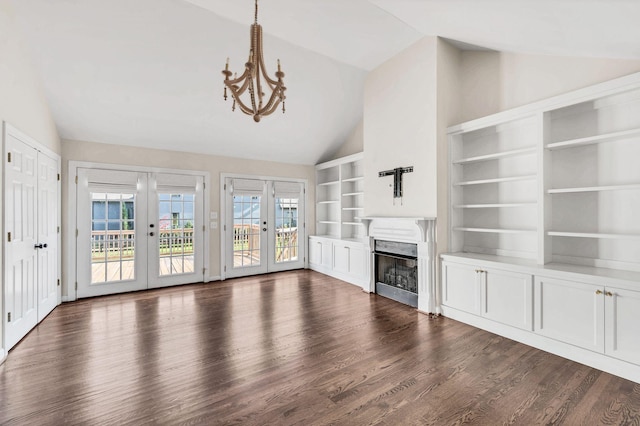 unfurnished living room with dark wood-type flooring, french doors, an inviting chandelier, lofted ceiling, and built in shelves