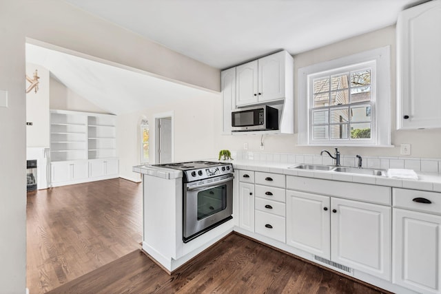 kitchen featuring dark wood-type flooring, tile counters, white cabinets, appliances with stainless steel finishes, and sink