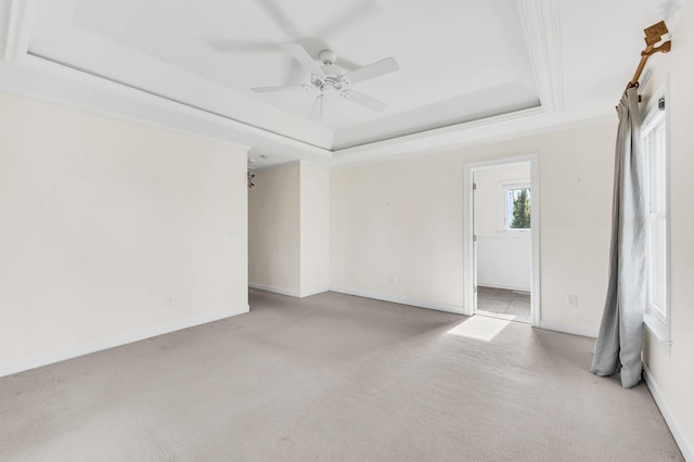 spare room with ceiling fan, light colored carpet, ornamental molding, and a tray ceiling