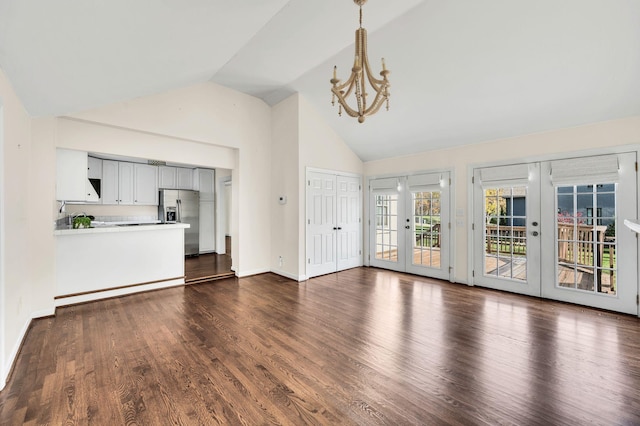 unfurnished living room featuring a notable chandelier, dark wood-type flooring, french doors, and high vaulted ceiling