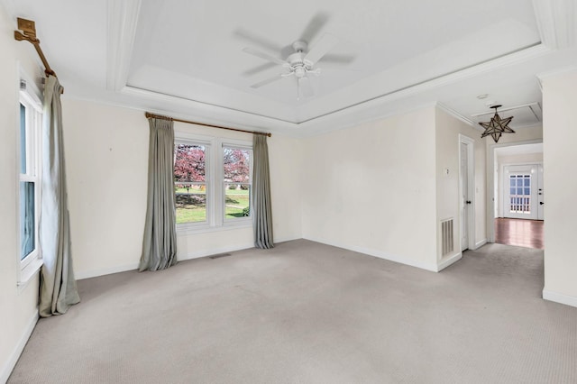 unfurnished room with ceiling fan, light colored carpet, ornamental molding, and a tray ceiling