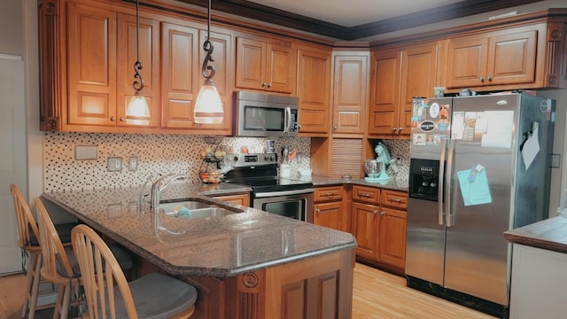 kitchen featuring dark stone counters, a kitchen breakfast bar, sink, decorative light fixtures, and stainless steel appliances