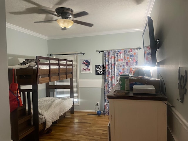 bedroom with ceiling fan, hardwood / wood-style floors, a textured ceiling, and ornamental molding