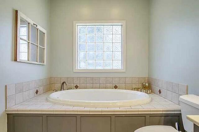 bathroom with a washtub, vanity, and toilet