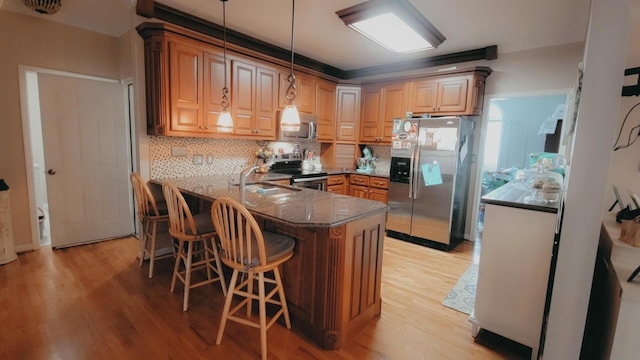 kitchen featuring kitchen peninsula, a breakfast bar, stainless steel appliances, and light hardwood / wood-style flooring