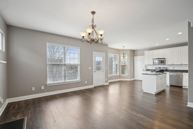 kitchen featuring an inviting chandelier, white cabinets, hanging light fixtures, decorative backsplash, and stainless steel appliances