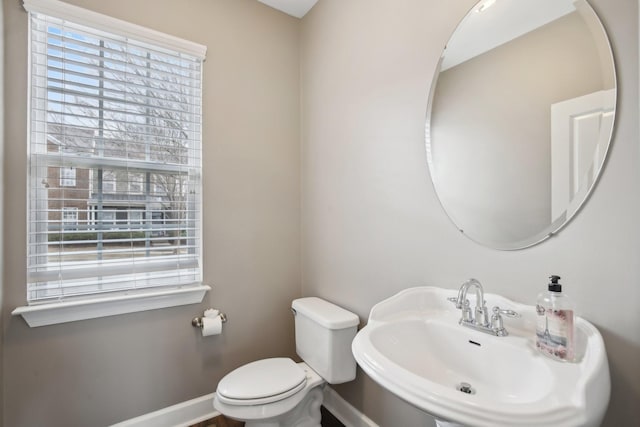 bathroom with toilet, a wealth of natural light, and sink