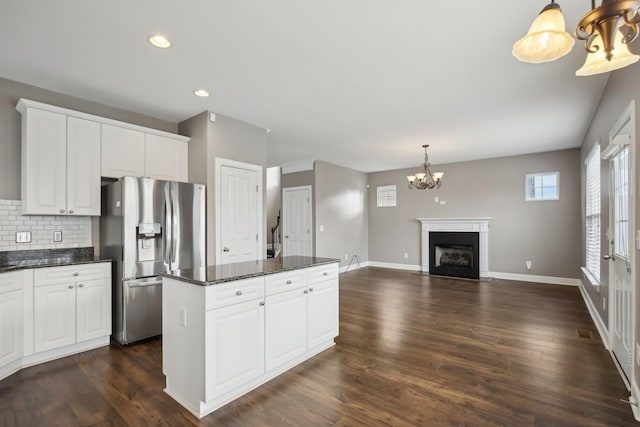 kitchen featuring hanging light fixtures, an inviting chandelier, stainless steel fridge with ice dispenser, dark stone countertops, and white cabinets