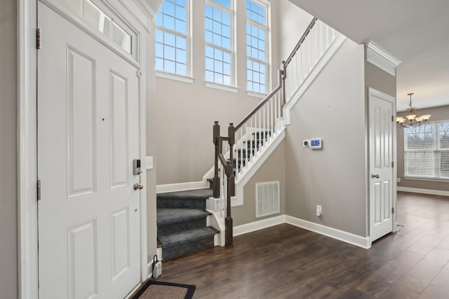 entryway featuring crown molding, dark hardwood / wood-style flooring, and an inviting chandelier