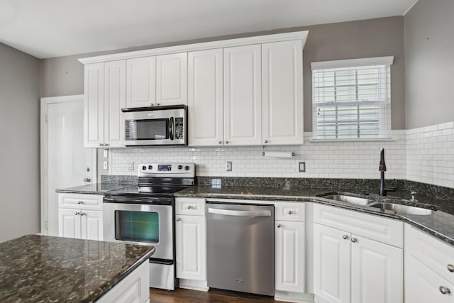 kitchen featuring white cabinets, dark stone countertops, sink, and appliances with stainless steel finishes