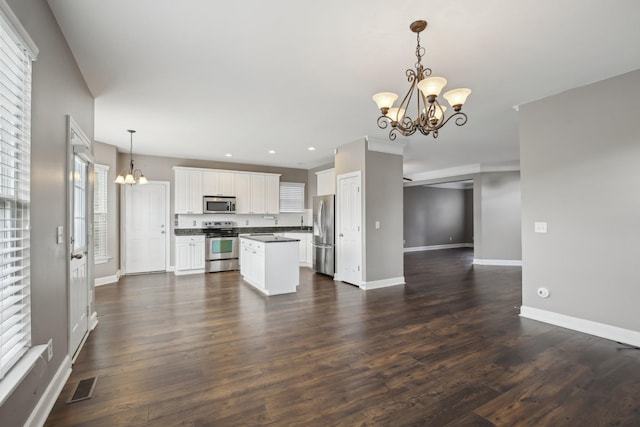 kitchen featuring pendant lighting, an inviting chandelier, appliances with stainless steel finishes, dark hardwood / wood-style flooring, and white cabinetry