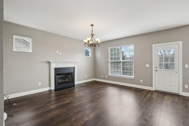 unfurnished living room with dark hardwood / wood-style floors and an inviting chandelier