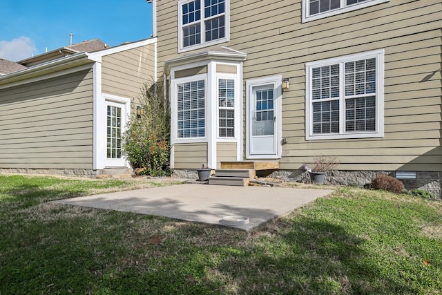 view of exterior entry featuring a yard and a patio