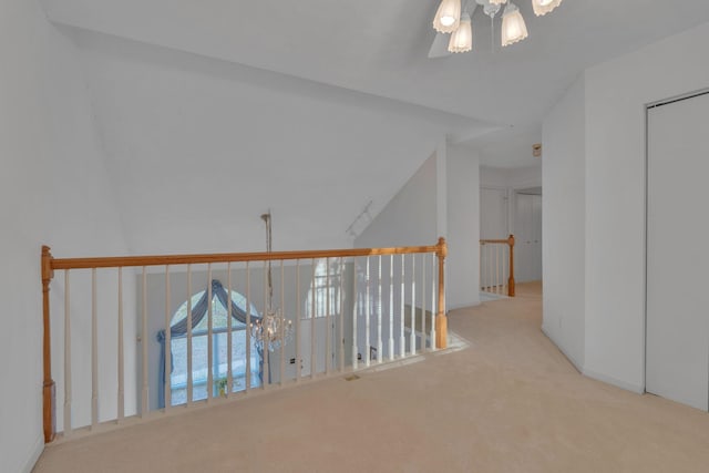 hallway featuring light carpet and a chandelier