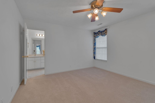 unfurnished bedroom featuring sink, ceiling fan, light colored carpet, and ensuite bathroom