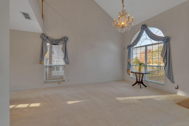 carpeted spare room featuring high vaulted ceiling and a chandelier