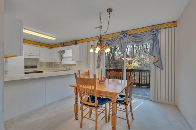 carpeted dining room with a chandelier, a wealth of natural light, and sink