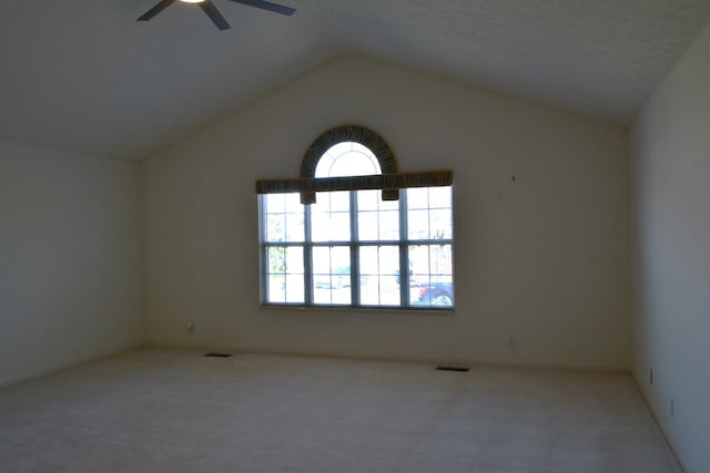 spare room featuring a textured ceiling, light colored carpet, ceiling fan, and lofted ceiling