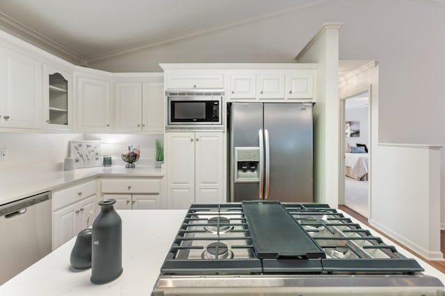 kitchen with white cabinetry, crown molding, stainless steel appliances, and lofted ceiling