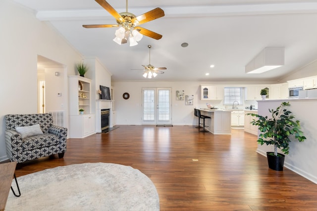 living room with dark wood-type flooring, french doors, vaulted ceiling with beams, ceiling fan, and ornamental molding