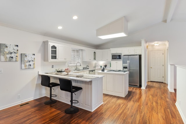 kitchen with lofted ceiling with beams, a kitchen breakfast bar, white cabinetry, and stainless steel appliances