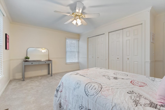 bedroom with ceiling fan, light carpet, two closets, and ornamental molding