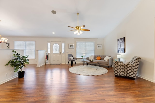 living room with lofted ceiling, ceiling fan with notable chandelier, dark hardwood / wood-style floors, and ornamental molding