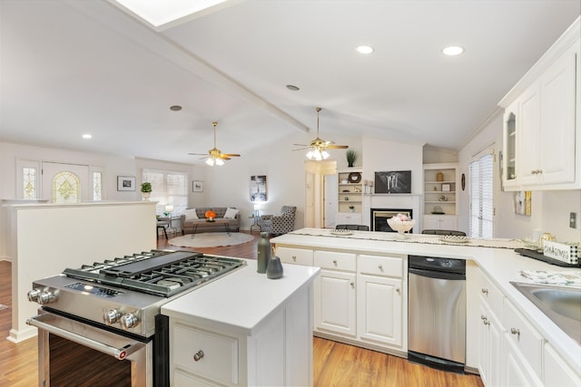 kitchen featuring white cabinets, stainless steel gas stove, lofted ceiling with beams, and light hardwood / wood-style floors