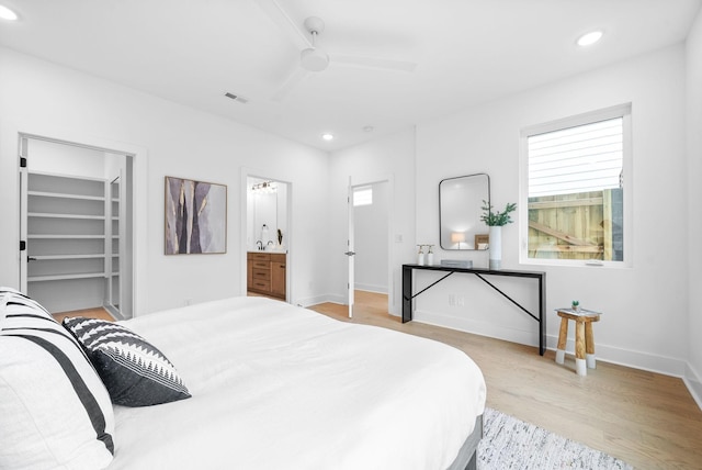 bedroom featuring a walk in closet, ceiling fan, ensuite bath, and light hardwood / wood-style floors