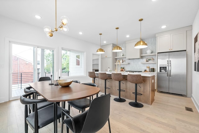 dining space featuring an inviting chandelier, light hardwood / wood-style flooring, and sink