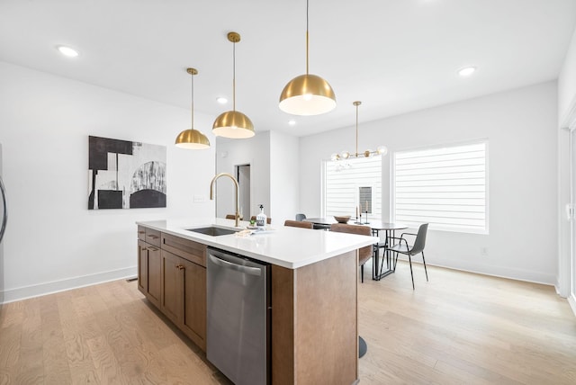 kitchen featuring light wood-type flooring, stainless steel dishwasher, a kitchen island with sink, and sink