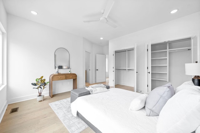 bedroom with multiple closets, ceiling fan, and light wood-type flooring