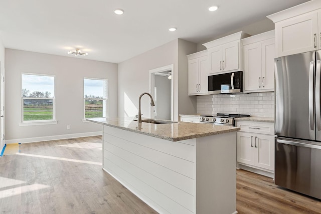 kitchen with white cabinets, appliances with stainless steel finishes, a center island with sink, and sink