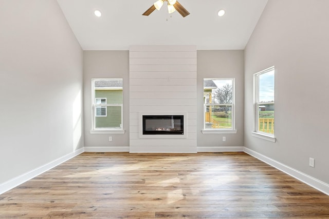 unfurnished living room with a fireplace, vaulted ceiling, light hardwood / wood-style flooring, and ceiling fan