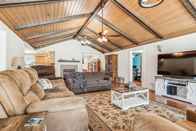 living room featuring ceiling fan, a fireplace, beamed ceiling, wood-type flooring, and wood ceiling