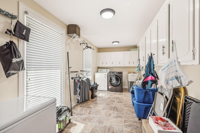 washroom with cabinets, independent washer and dryer, and sink